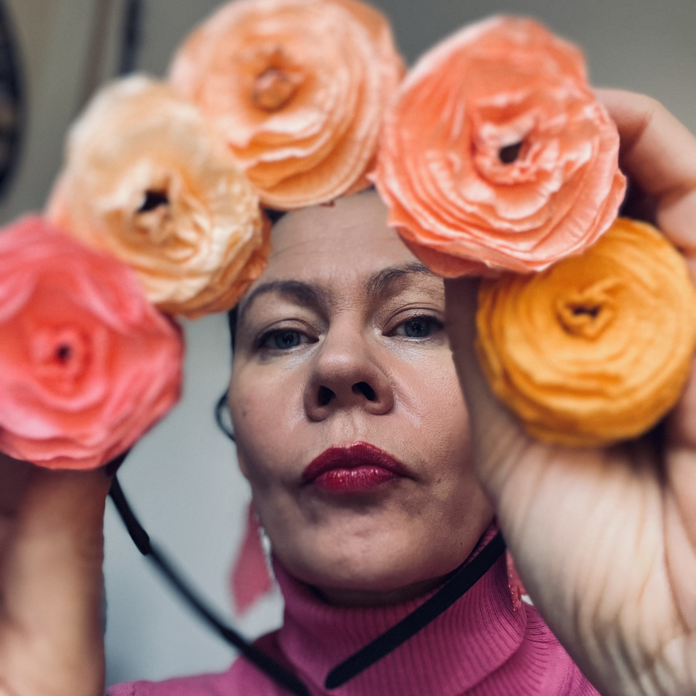 Kvinna håller upp ett blomsterdiadem i olika aprikosa toner.