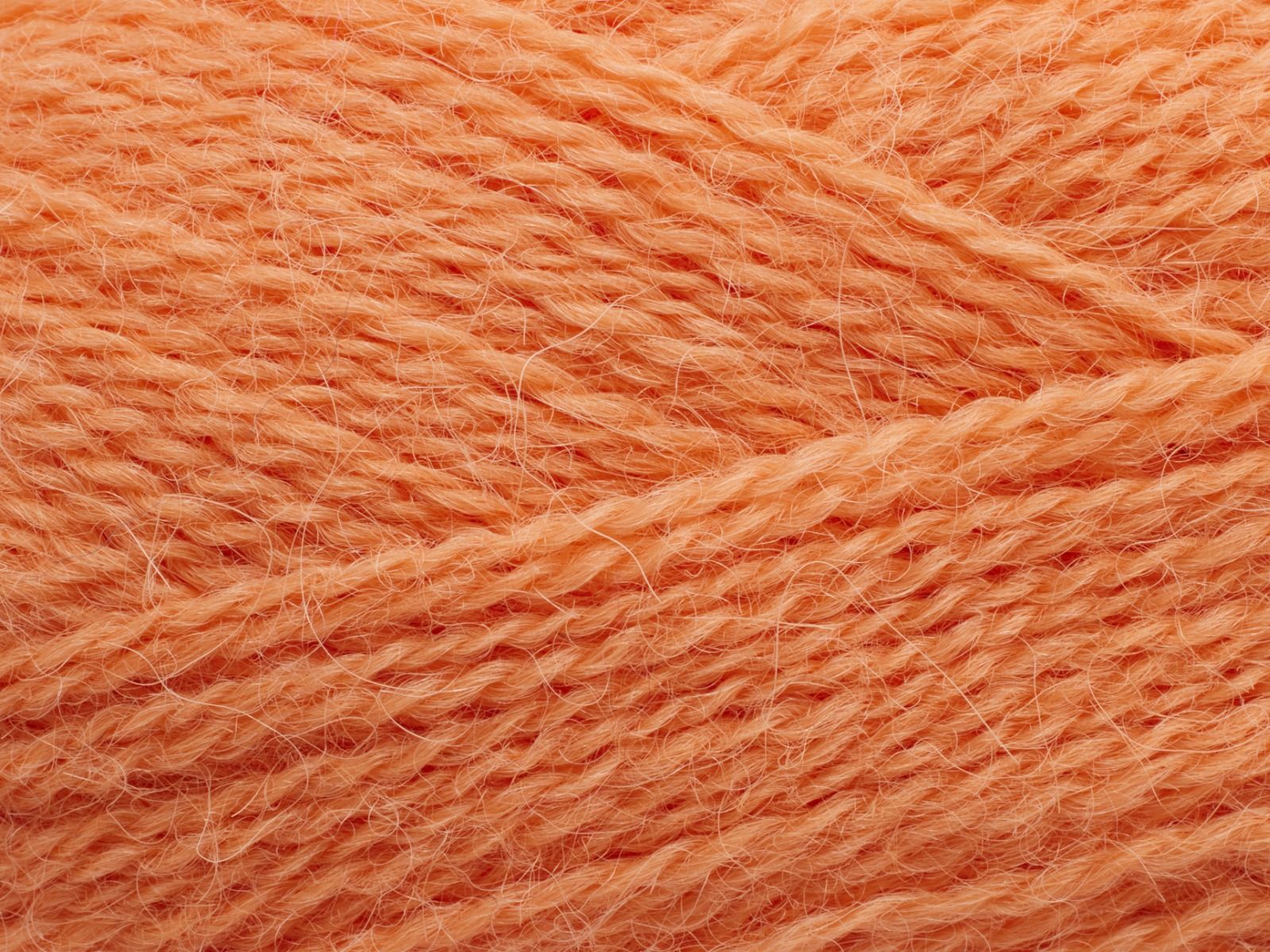En närbild på Filcolanas tunna alpackagarn Alva i ljust orange aprikos