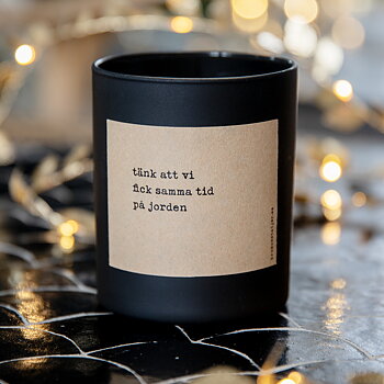 Doftljus med etikett i naturpapper och texten "Tänk att vi fick samma tid på jorden"