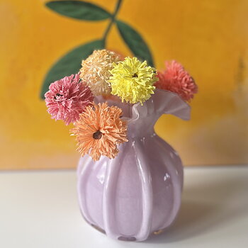 Bilden visar en lila vas med krysantemum i olika färger, gjorda av papper.