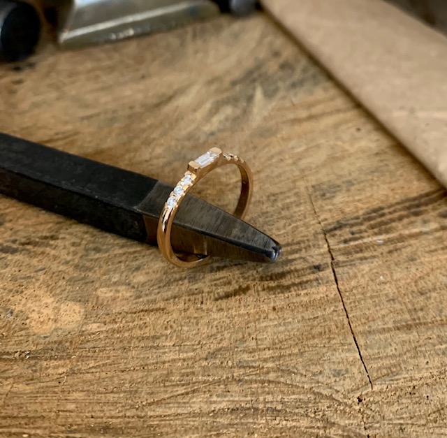 Ring Michelle stående mot en smyckesstämpel i metall