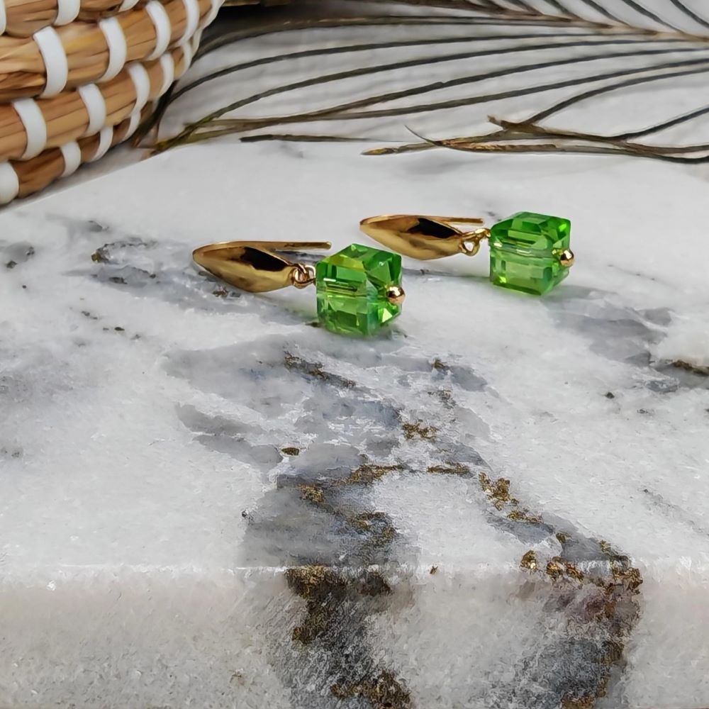Minimalistiska kubörhängen i förgyllt rostfritt stål med gröna glaspärlor.