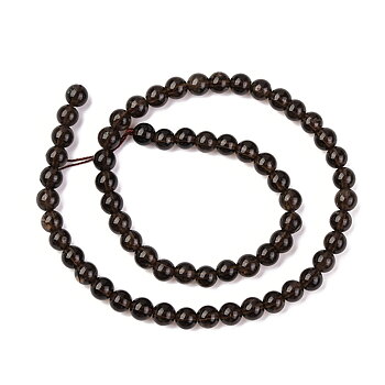 Sträng med runda rökkvarts-pärlor, 6 mm stora, i mörk transparent brun nyans, utlagd i spiralform på vit bakgrund.