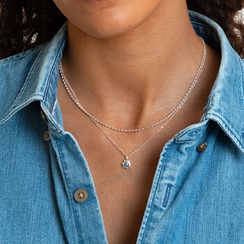 Syster P Lunetta halsband silver, enkelt kedjehalsband med små ovala länkar, stylat i lager med ett halsband med blå sten mot denimskjorta.