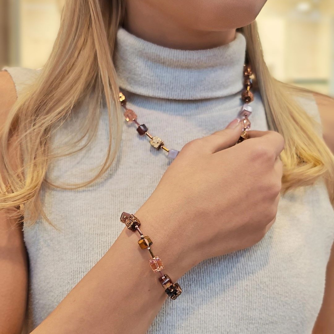 IAMLUND Chromatic halsband vinröd/brun på modell, handgjort kubhalsband i glas, lavasten, Polarispärlor och hematit i vinröda, guldiga och ljuslila nyanser.