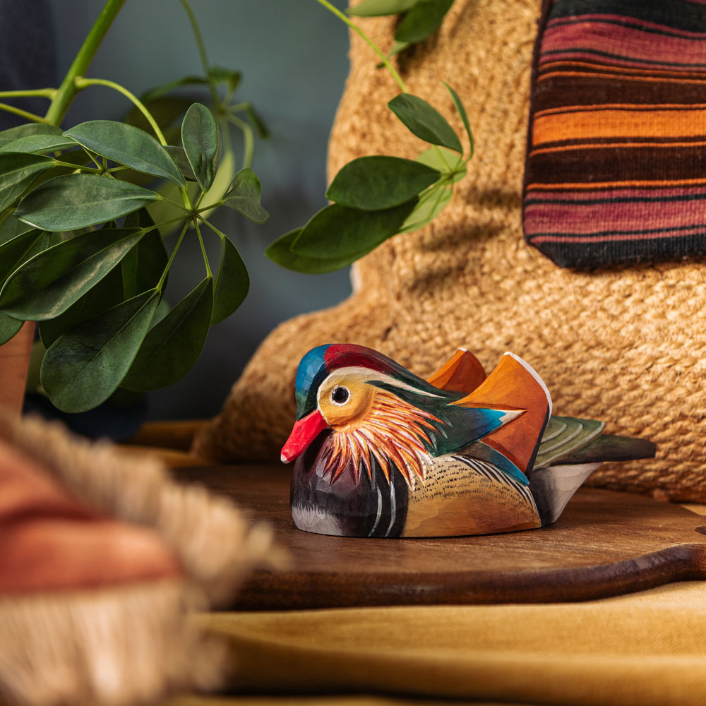 DecoBird Mandarin Duck displayed as décor in a still-life setting, surrounded by plants, textiles and natural materials.