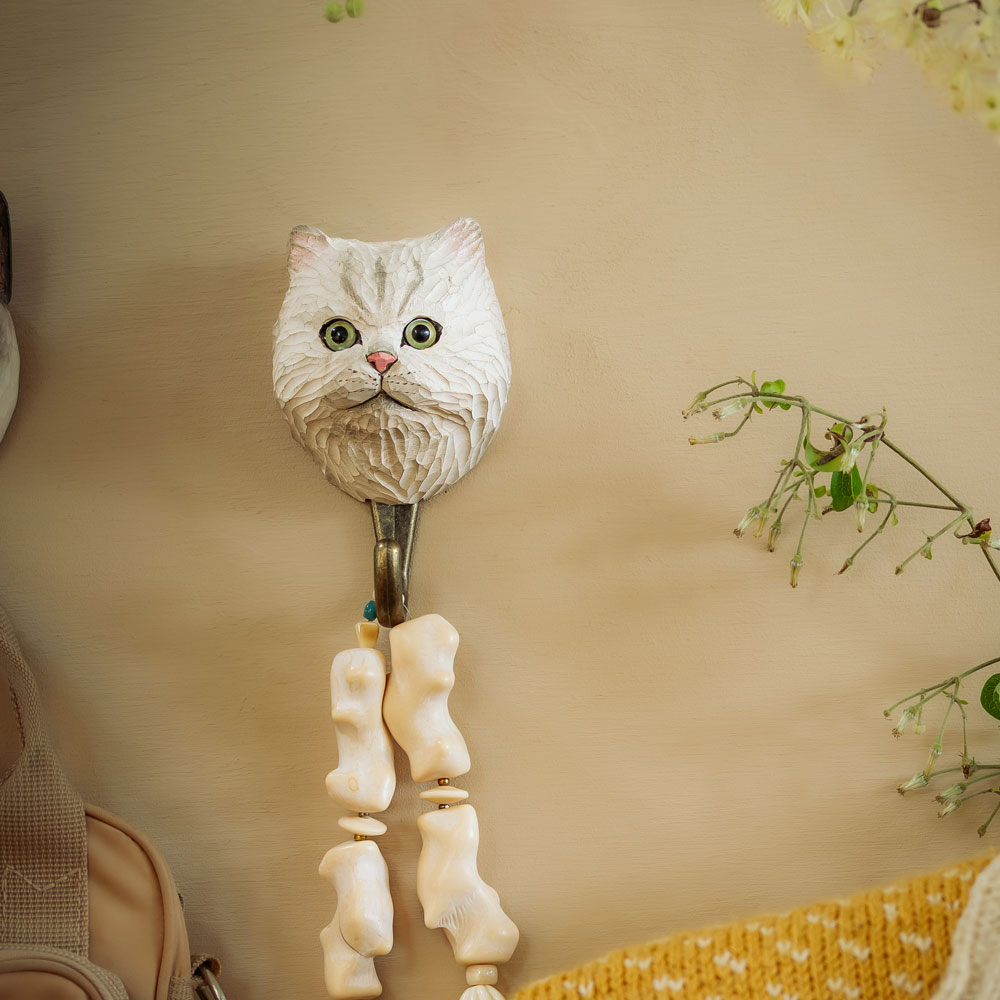Patère Chat Persan en mise en scène, fixée au mur avec des éléments décoratifs autour.