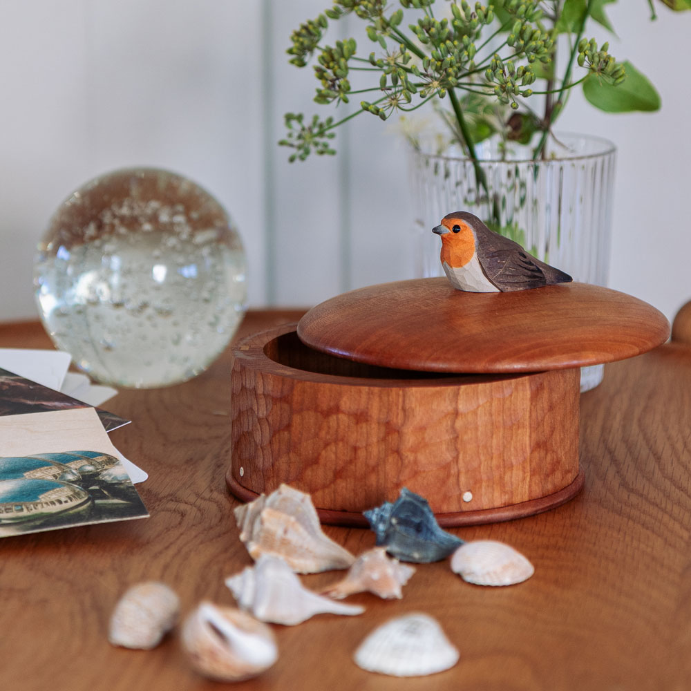 Wooden Box Robin in a lifestyle setting, with the lid open and the hand-carved robin on top, surrounded by shells and decorative objects.