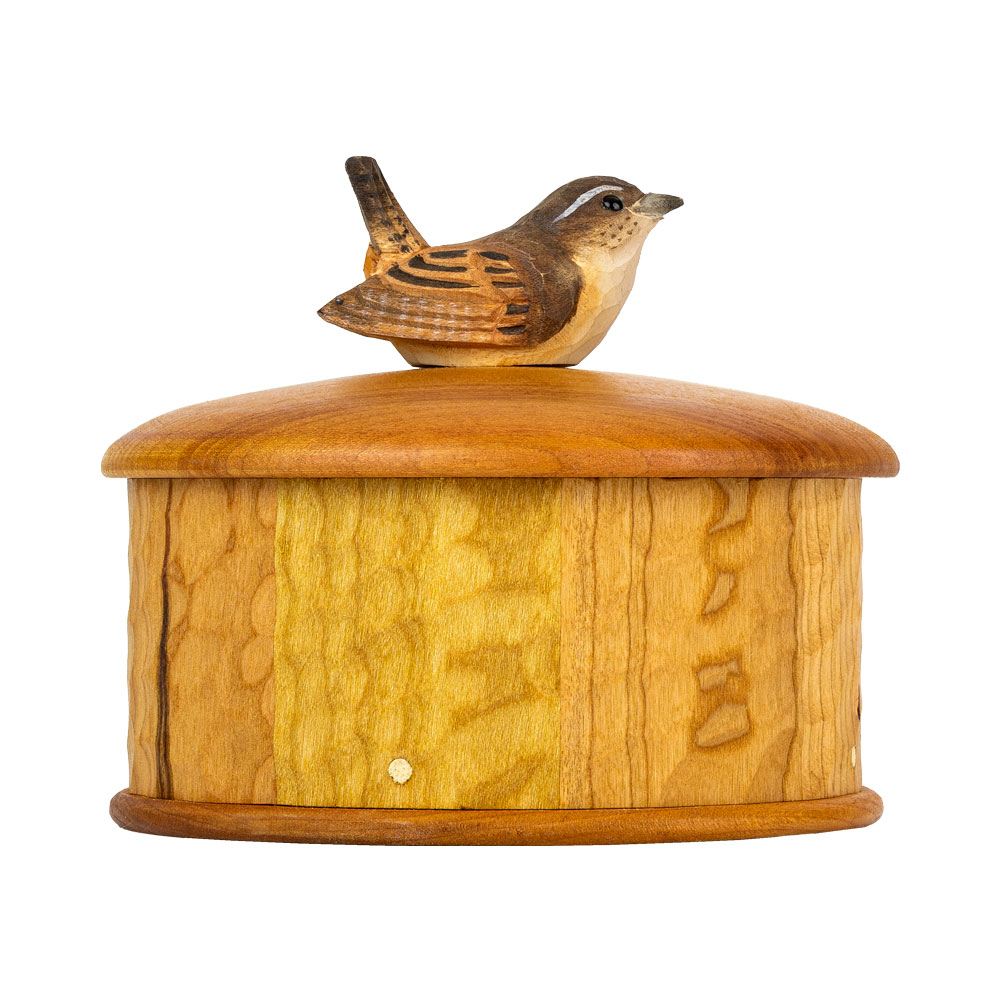 Coffret Troglodyte Mignon vu de côté, avec la boîte ronde en bois de cerisier et le troglodyte sculpté à la main sur le couvercle.
