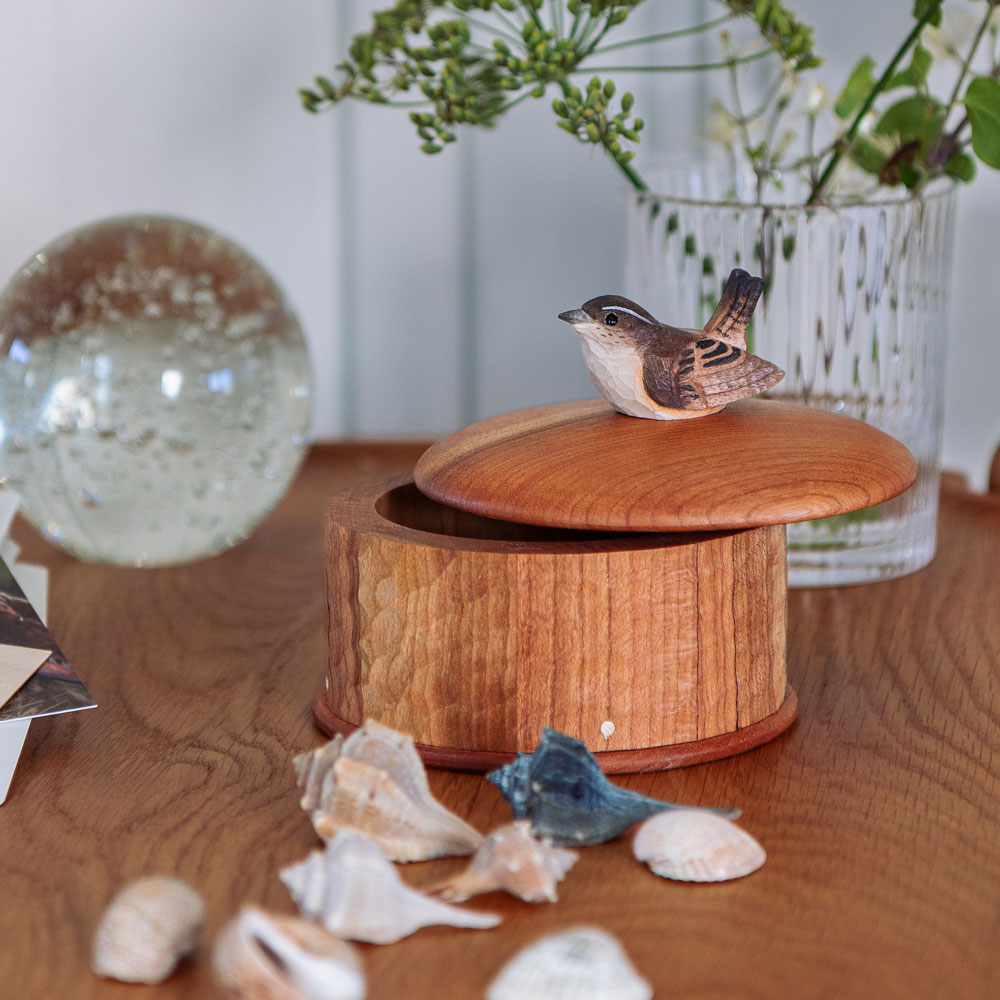 Wooden Box Wren in a lifestyle setting, shown open on the table with the hand-carved wren resting on the lid.