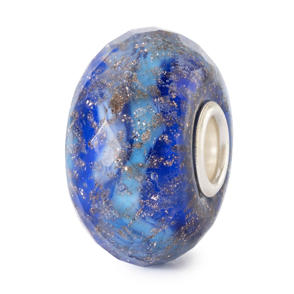Trollbeads Starlight Ocean glaskula TGLBE-30001 – fasetterad pärla i djupblått och turkost glas med gyllene stänk, visad i närbild mot vit bakgrund.