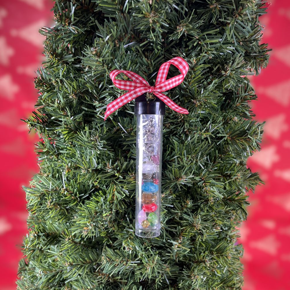 Angel Surprise Tube smyckeskit, genomskinliga rör fyllda med pärlor och smyckesdelar, dekorerade med rödrutiga rosetter, hängande i en grön julgran.