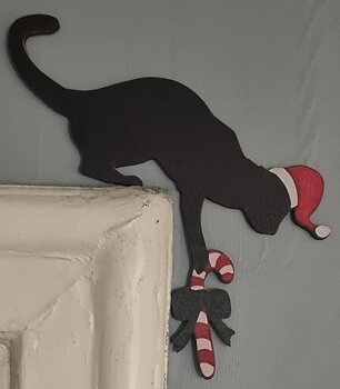 Skylt i träfaner att sätta ovanför dörrfodret "Julkatt med polkagris"