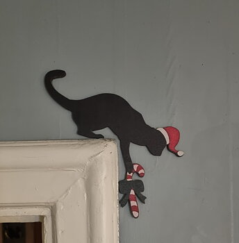 Skylt i träfaner att sätta ovanför dörrfodret "Julkatt med polkagris"