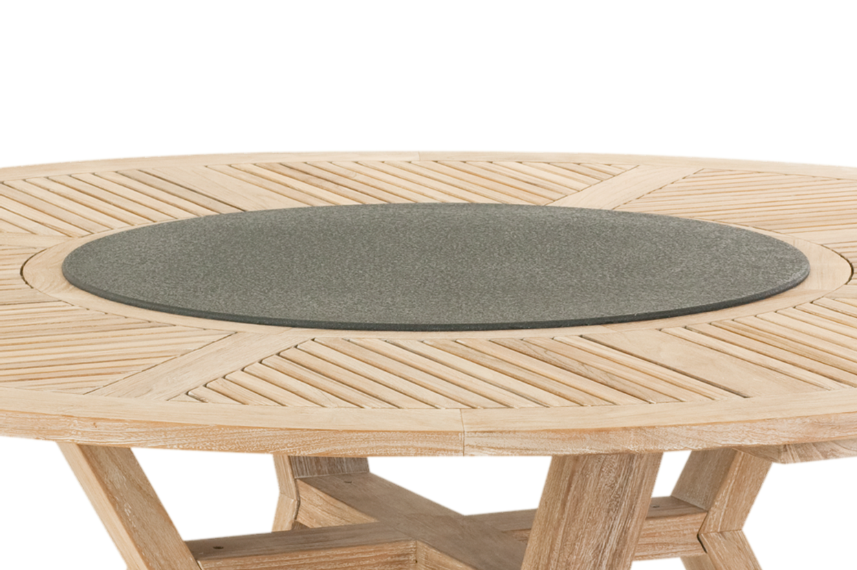 Närbild uppifrån av ett runt matbord i teak. Bordsskivan har ett dekorativt mönster av diagonala teakribbor i fält, och i mitten sitter en inbyggd rund snurrskiva i glas som är ytbehandlad så att den ser ut som grå sten.