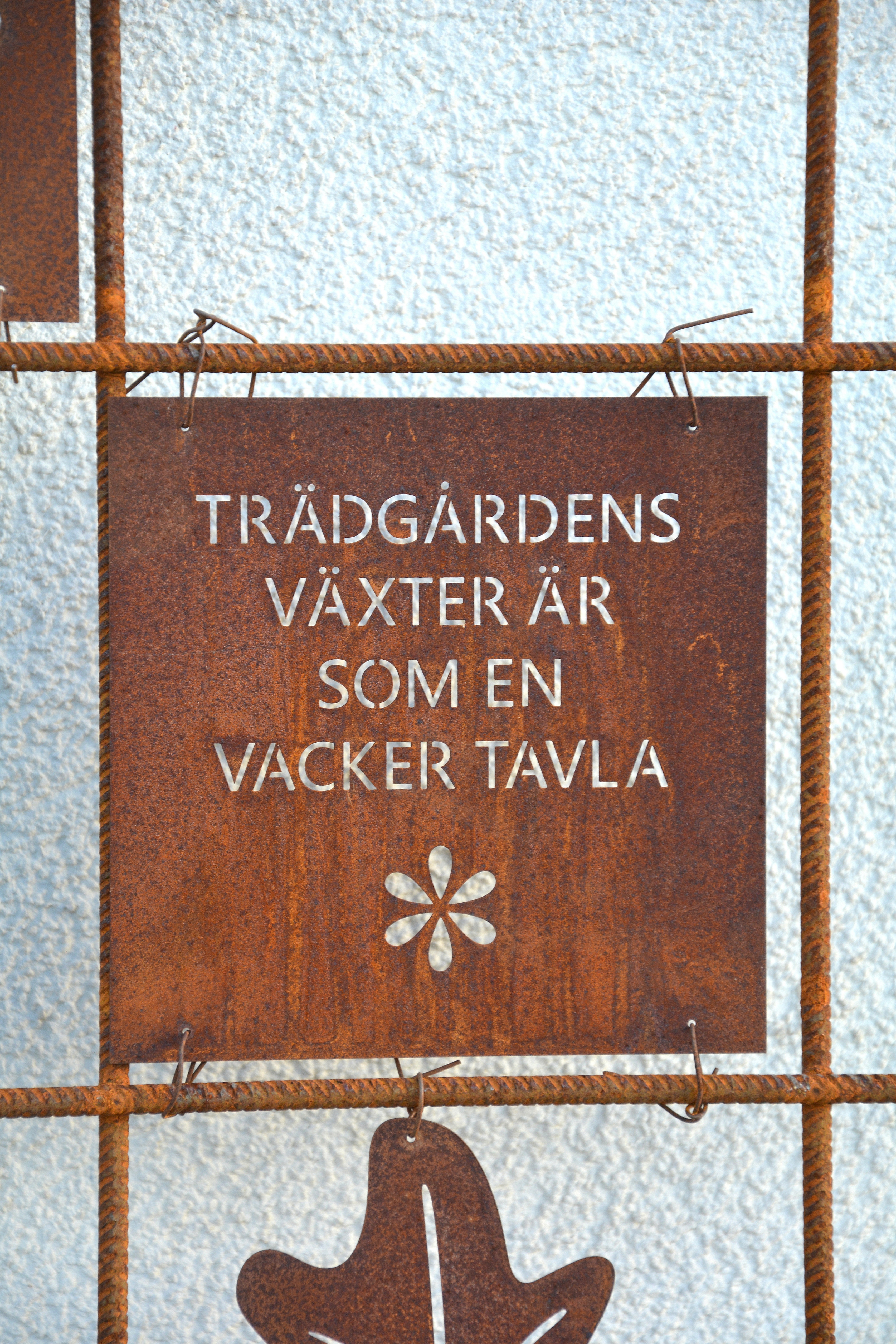 Rostig skylt till armeringsnät text: TRÄDGÅRDENS VÄXTER ÄR... 14 cm