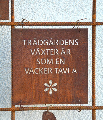 Rostig skylt till armeringsnät text: TRÄDGÅRDENS VÄXTER ÄR... 14 cm