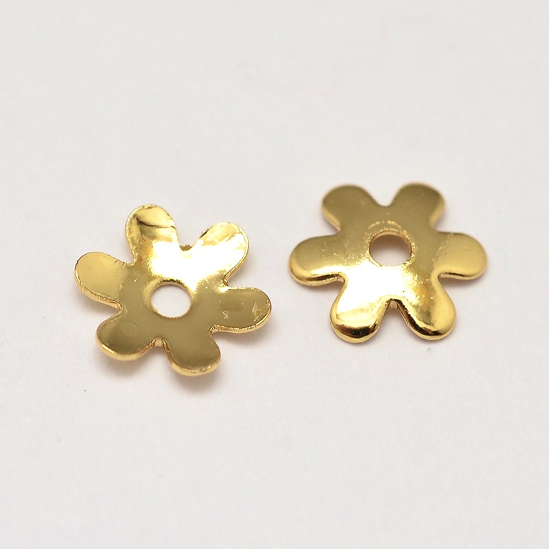 Pärlhattar i blomform med sex kronblad, 6 mm i förgyllt mässing, 20 stycken visade i närbild.