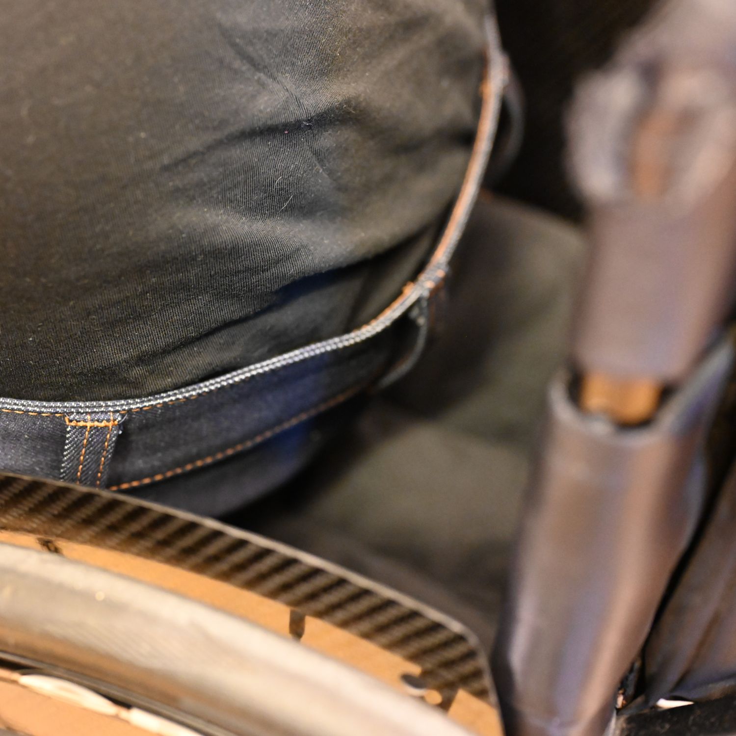 Dark blue wheelchair jeans on a person sitting in a wheelchair; 100% organic cotton; close-up of the back/waist
