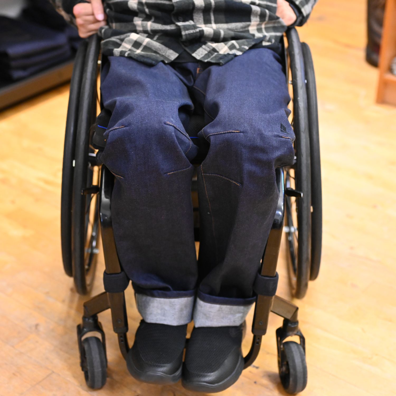 Dark blue wheelchair jeans on a person sitting in a wheelchair, 100% organic cotton, front view