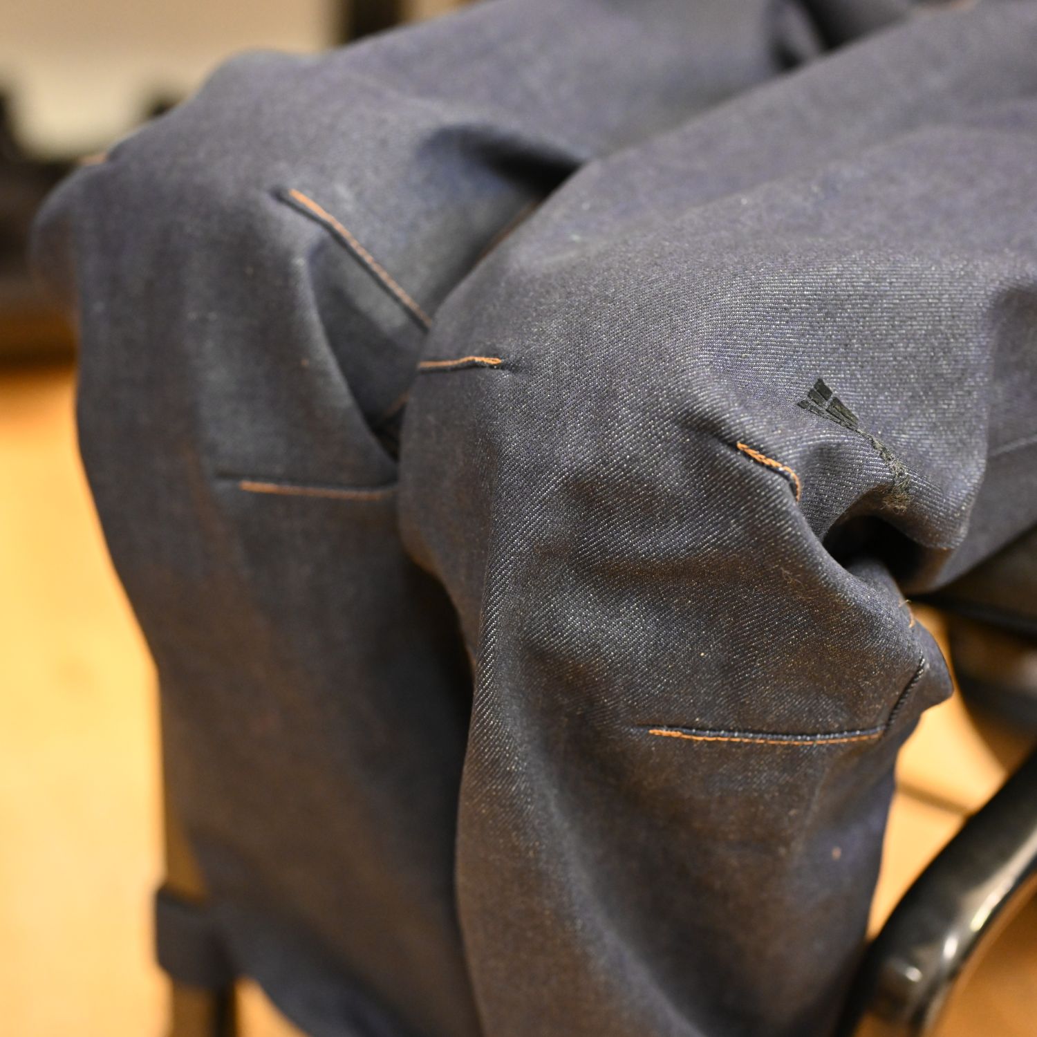 Dark blue wheelchair-accessible jeans on a person sitting in a wheelchair; 100% organic cotton; close-up of the contoured knees
