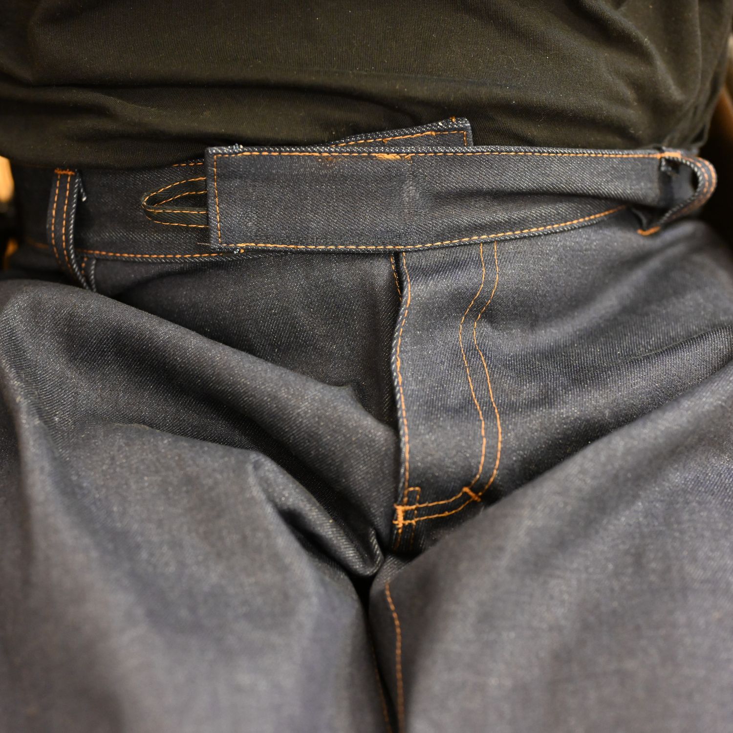 Dark blue wheelchair jeans on a person sitting in a wheelchair; 100% organic cotton; close-up of the open fly