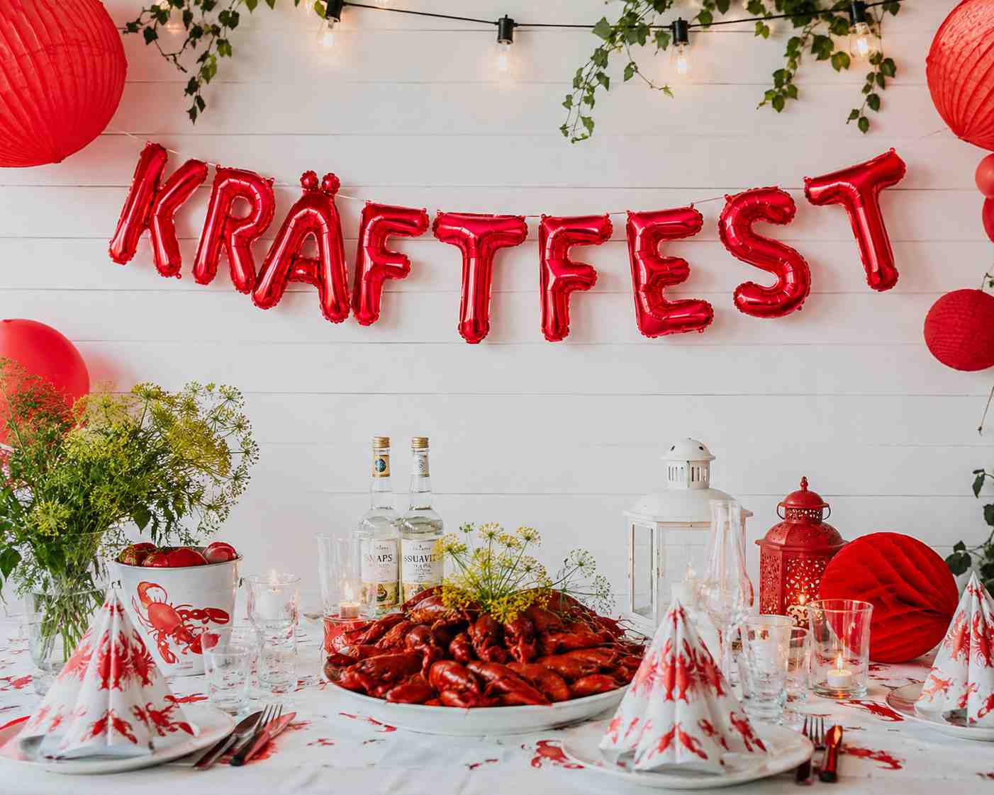 Kräftfest ballonggirlang i rött med folieballonger ovanför dukat kräftbord