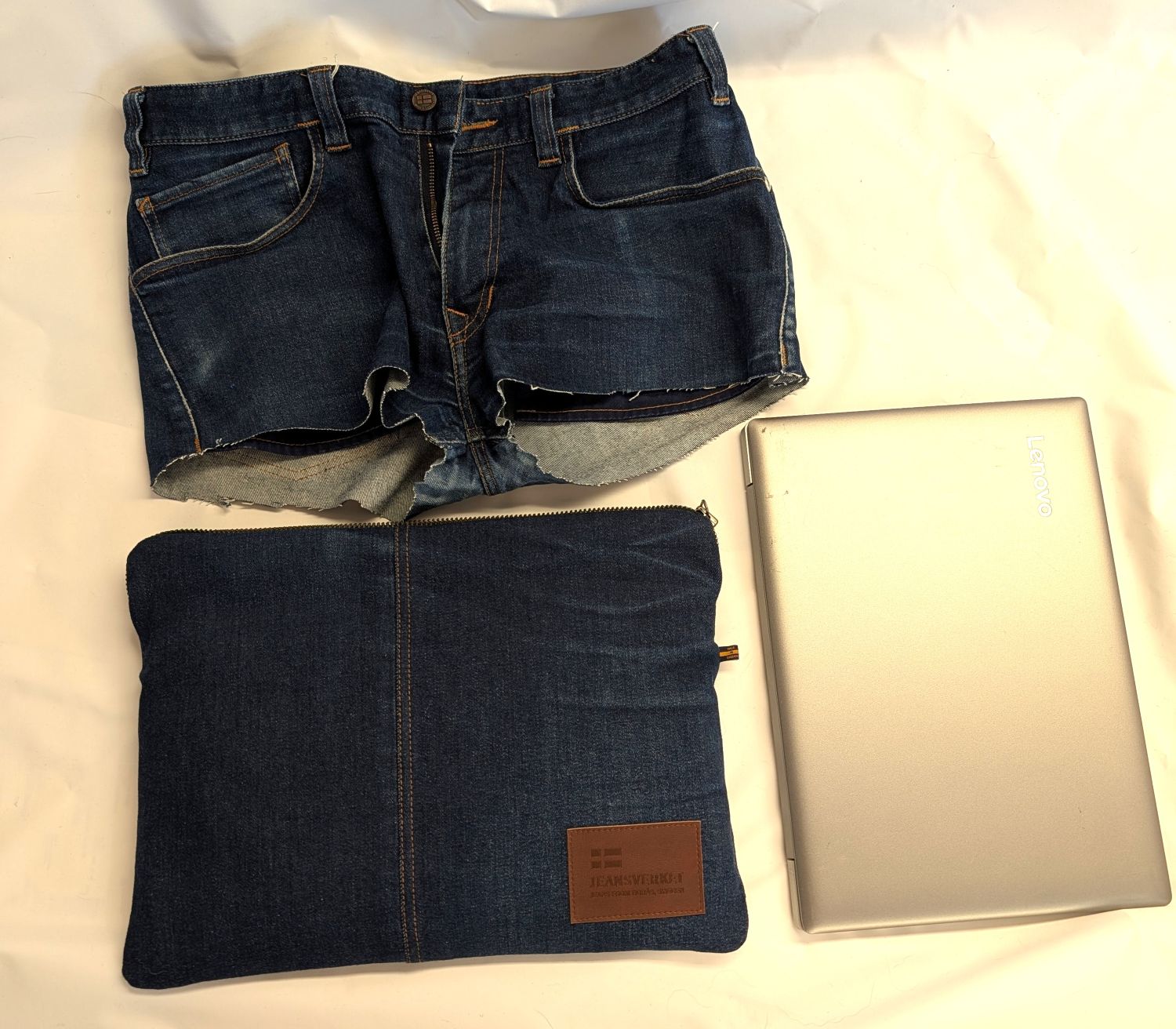 översiktsbild på fodral, en 14tums laptop och jeansen med avklippta ben som fodralets utsida är tillverkat av