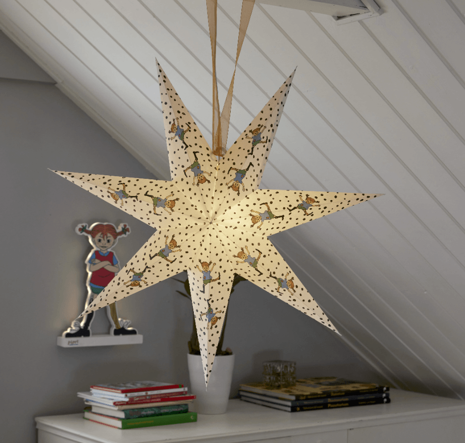 Illuminated Pippi Longstocking paper advent star hanging in a children's room with books.