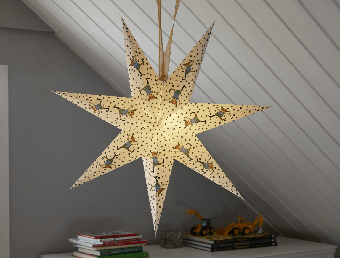 Glowing seven-pointed Christmas star featuring Pippi Longstocking suspended above a dresser with toys and books.