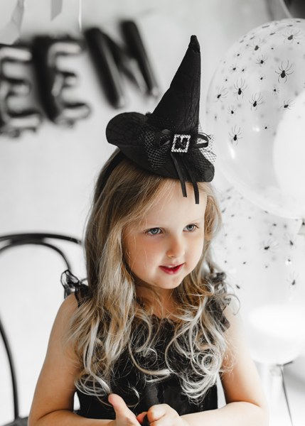 Barn med svart häxhatt på diadem till Halloween