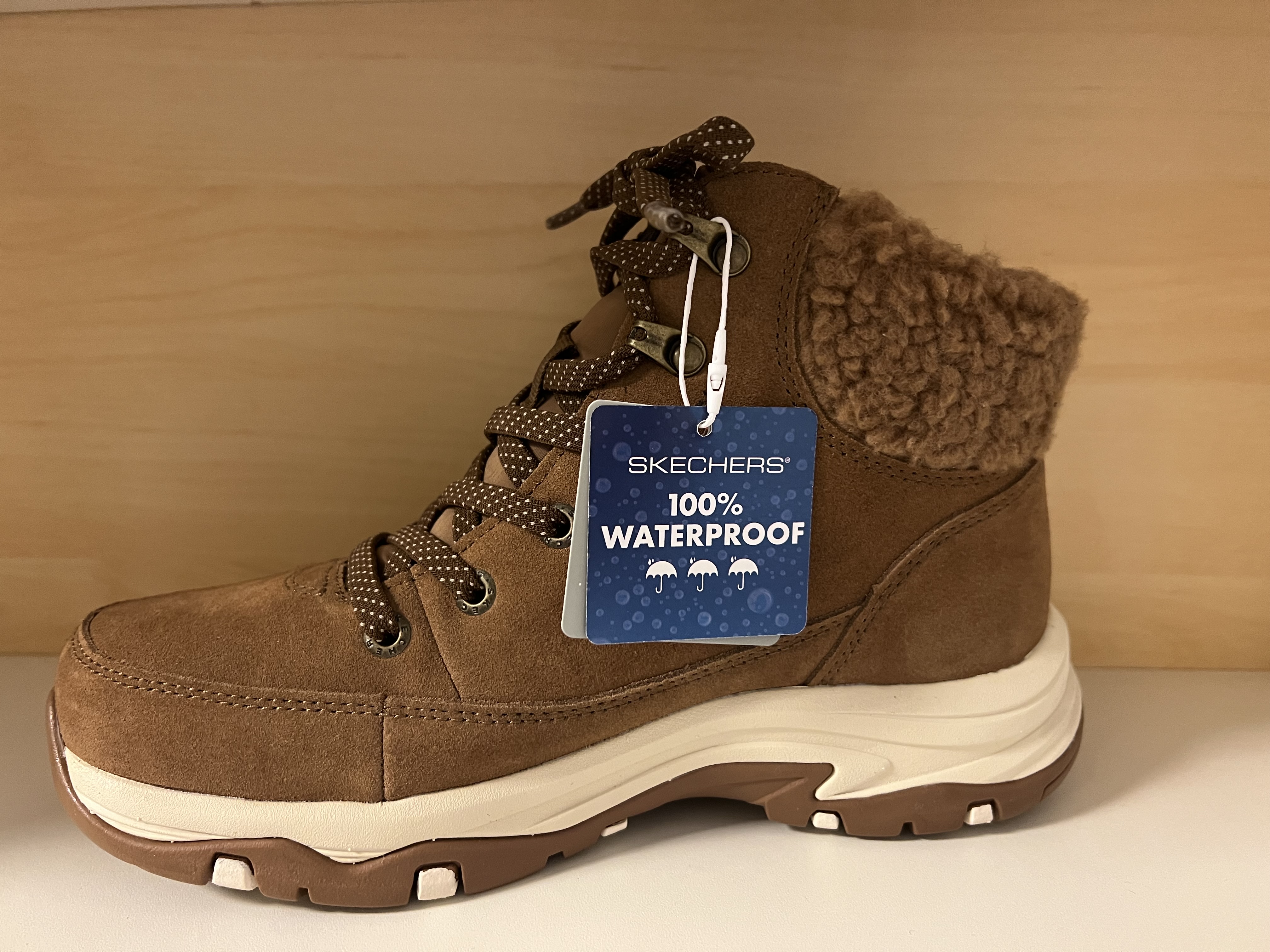 Skechers Damkänga i ljusbrun Waterproof mocka. Relaxes Fit Rymlig ovandel. Foder i fuskpäls med mjuk "krage" Slip-Ins samt justerbara snören. Stötdämpande Memory Foam innersula. - 2