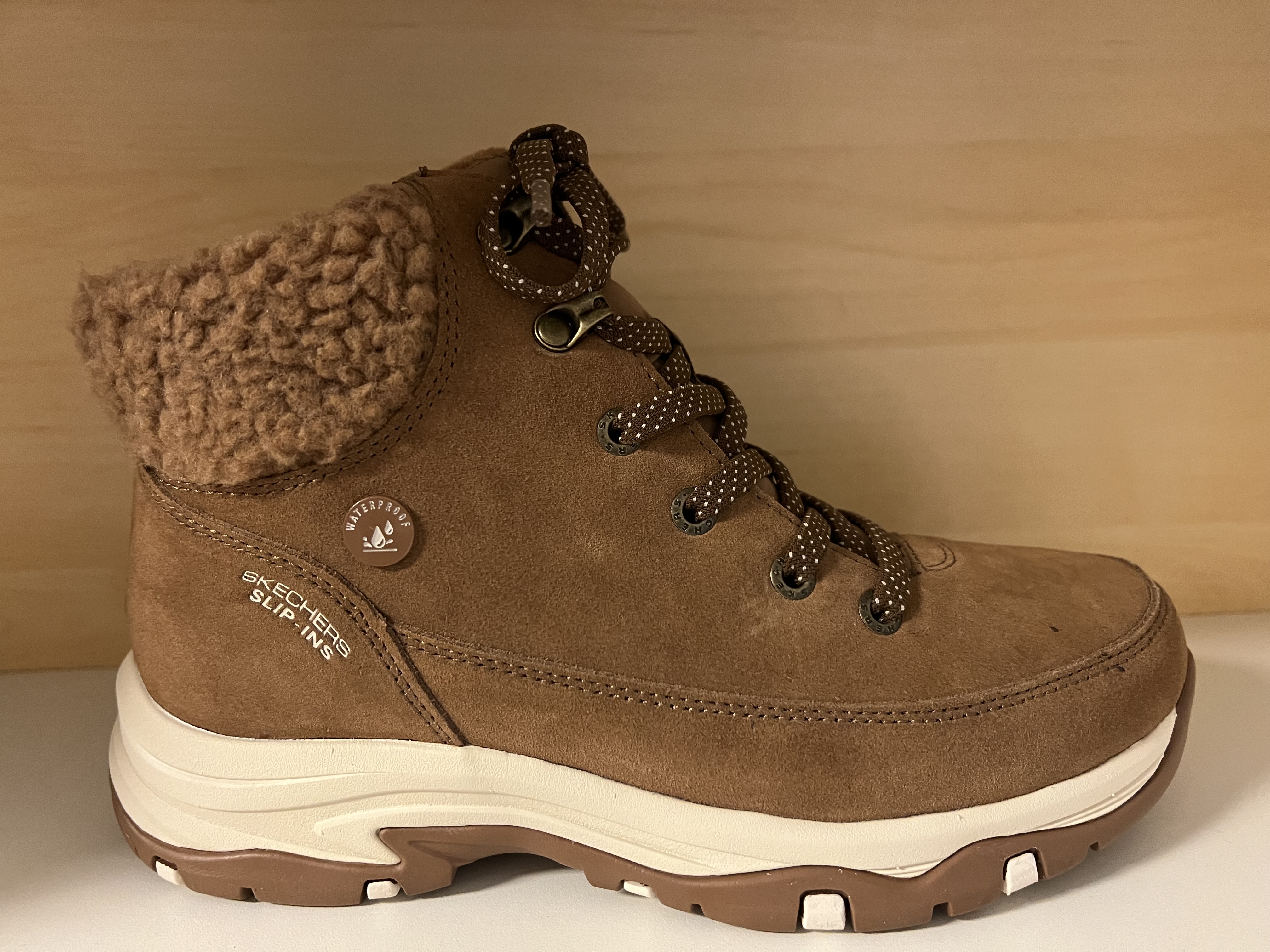 Skechers Damkänga i ljusbrun Waterproof mocka. Relaxes Fit Rymlig ovandel. Foder i fuskpäls med mjuk "krage" Slip-Ins samt justerbara snören. Stötdämpande Memory Foam innersula.