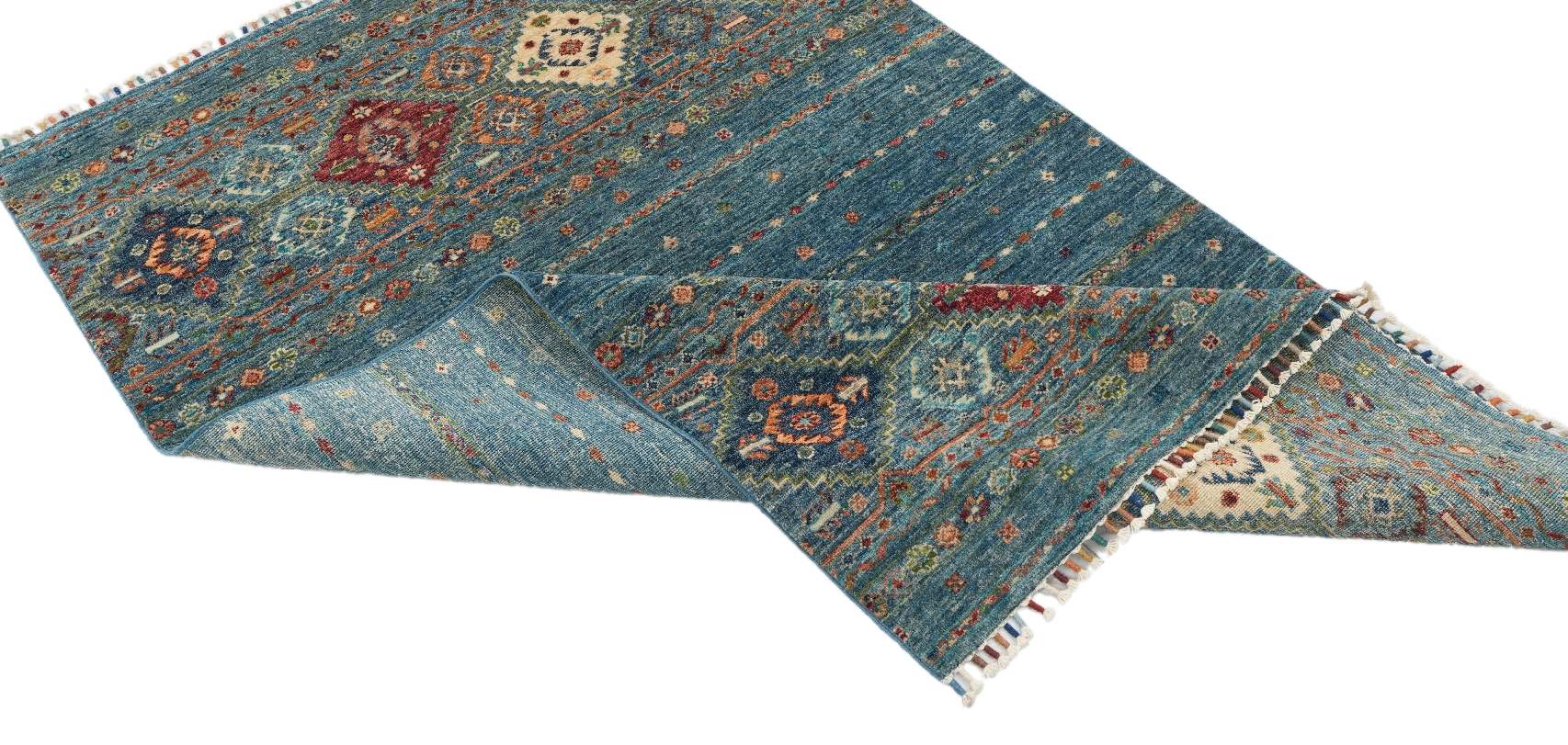 Detaljbild av Samarkand Blå 120x182 cm med uppvikt hörn som visar mattans handknutna baksida, ullstruktur och mönster.