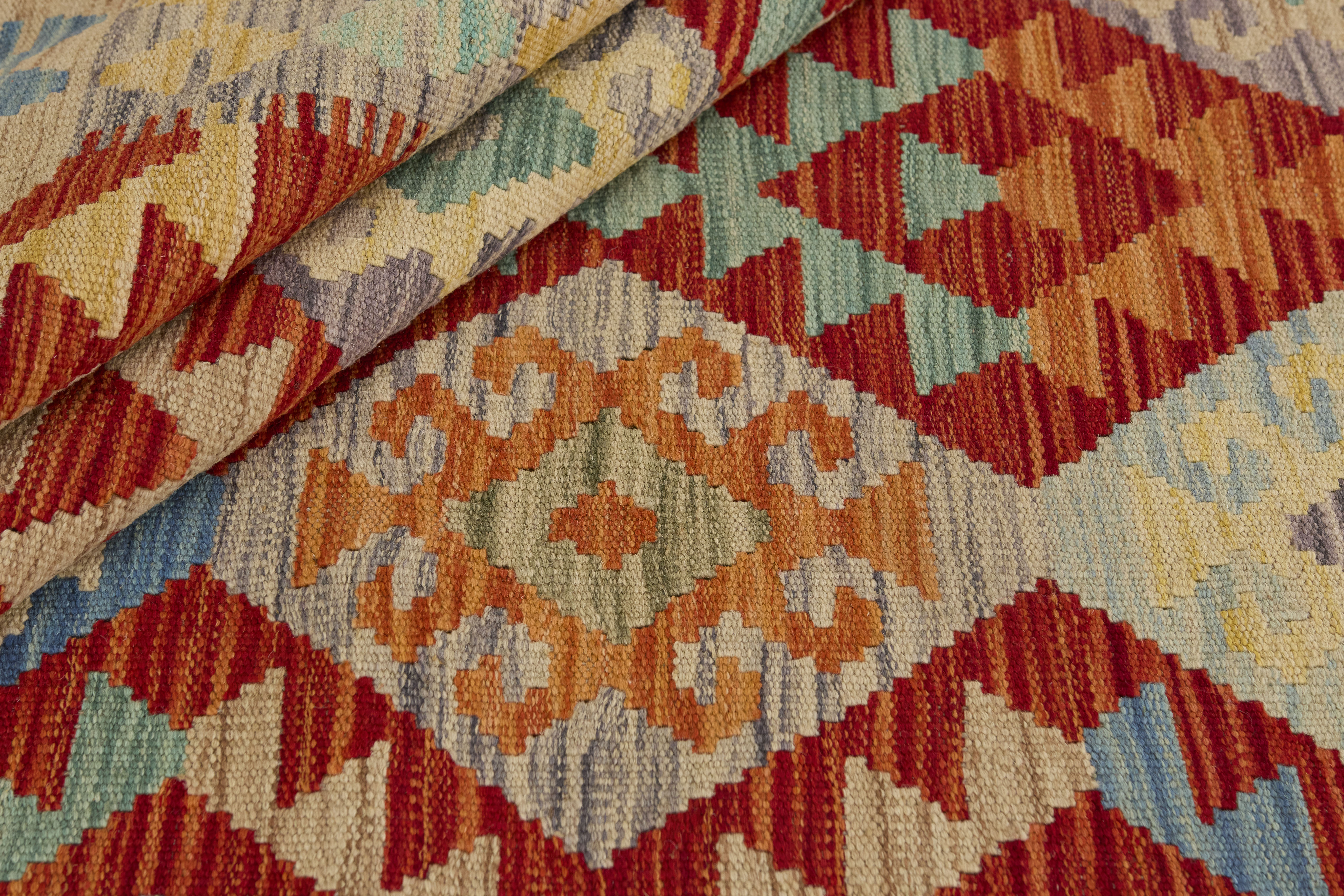 Närbild av Kelim 126x174 cm som visar ullvävens täta struktur och geometriska mönster i rött, blått, grönt, beige och orange.
