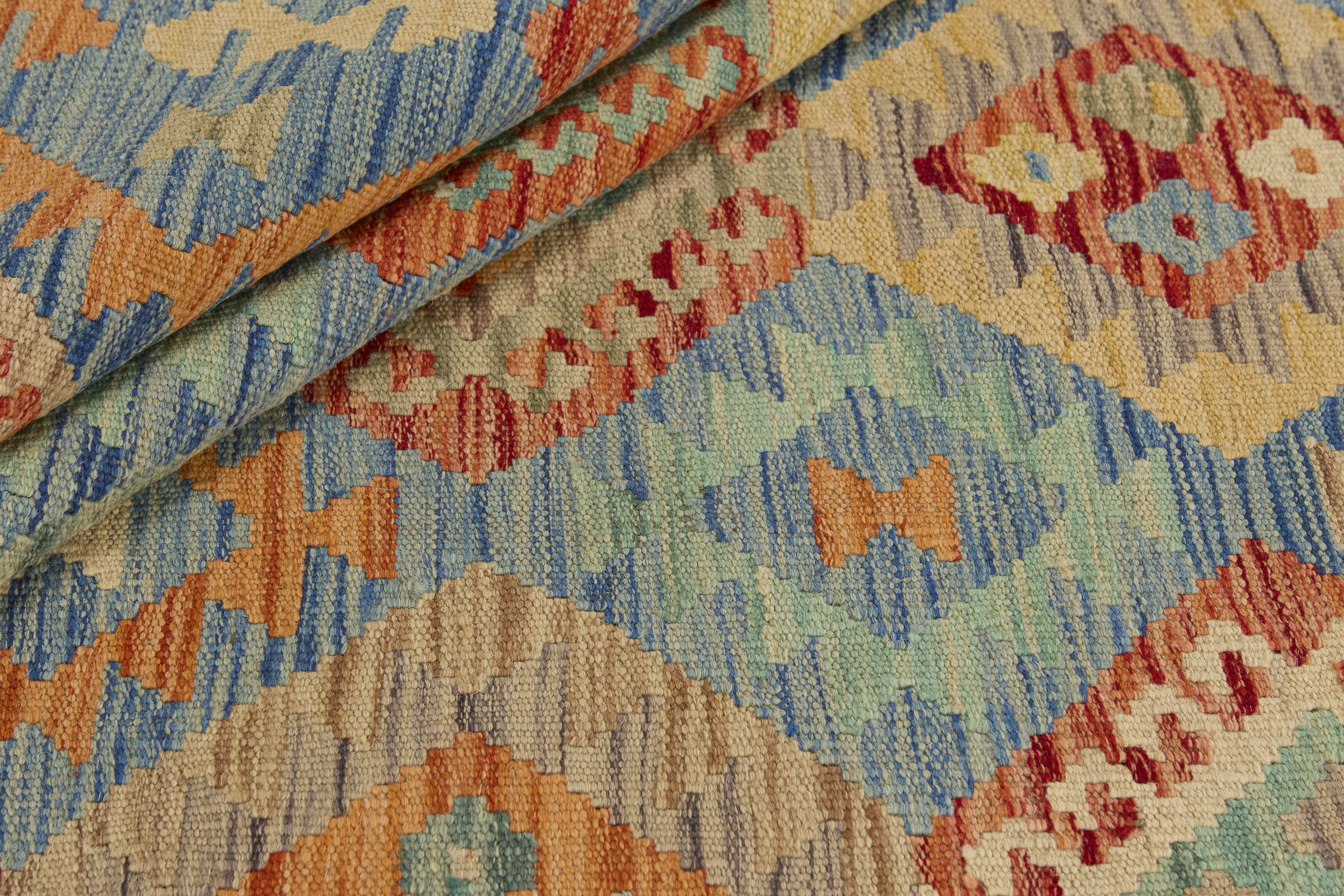 Närbild av Kelim 153x199 cm som visar den handvävda ullmattans struktur och geometriska mönster i blått, turkos, beige och terrakotta.