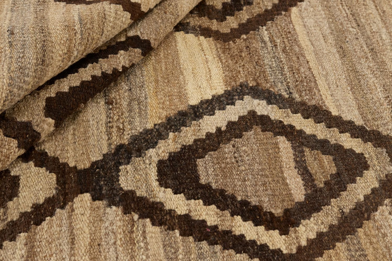 Närbild av Kelim 180x240 cm där mattans vikta ullväv visar den täta handvävda strukturen, naturliga färgskiftningar i beige och brunt samt det grafiska rombmönstret.