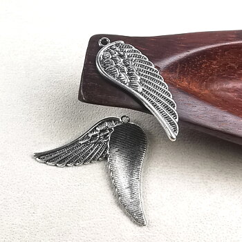 Tre antiksilverfärgade vingeberlocker i metall, cirka 15×44 mm med 2,5 mm hål, visade mot ljus bakgrund.