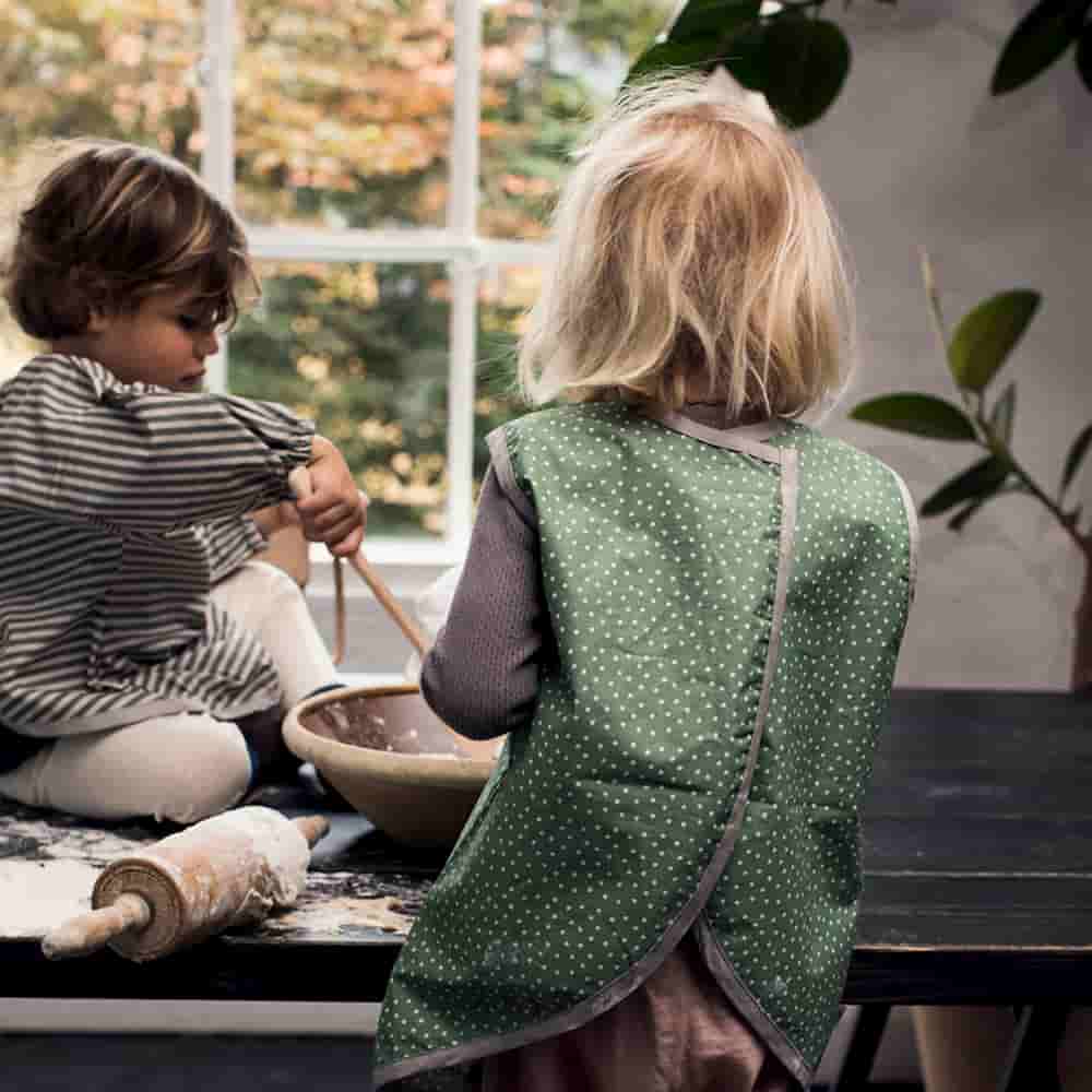 Lapset vihreillä pilkullisilla lasten esiliinalla