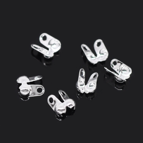 Knutgömma silverfärgad 6x4,5 mm, små metallkomponenter med ögla, visade i närbild på vit bakgrund.