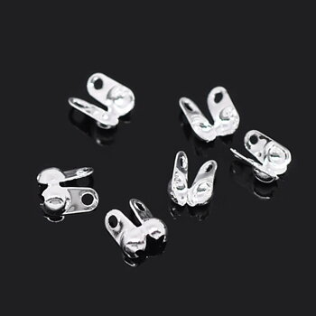 Knutgömma silverfärgad 6x4,5 mm, små metallkomponenter med ögla, visade i närbild på vit bakgrund.
