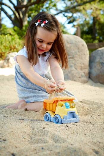 Barn leker med leksaksbil i sand