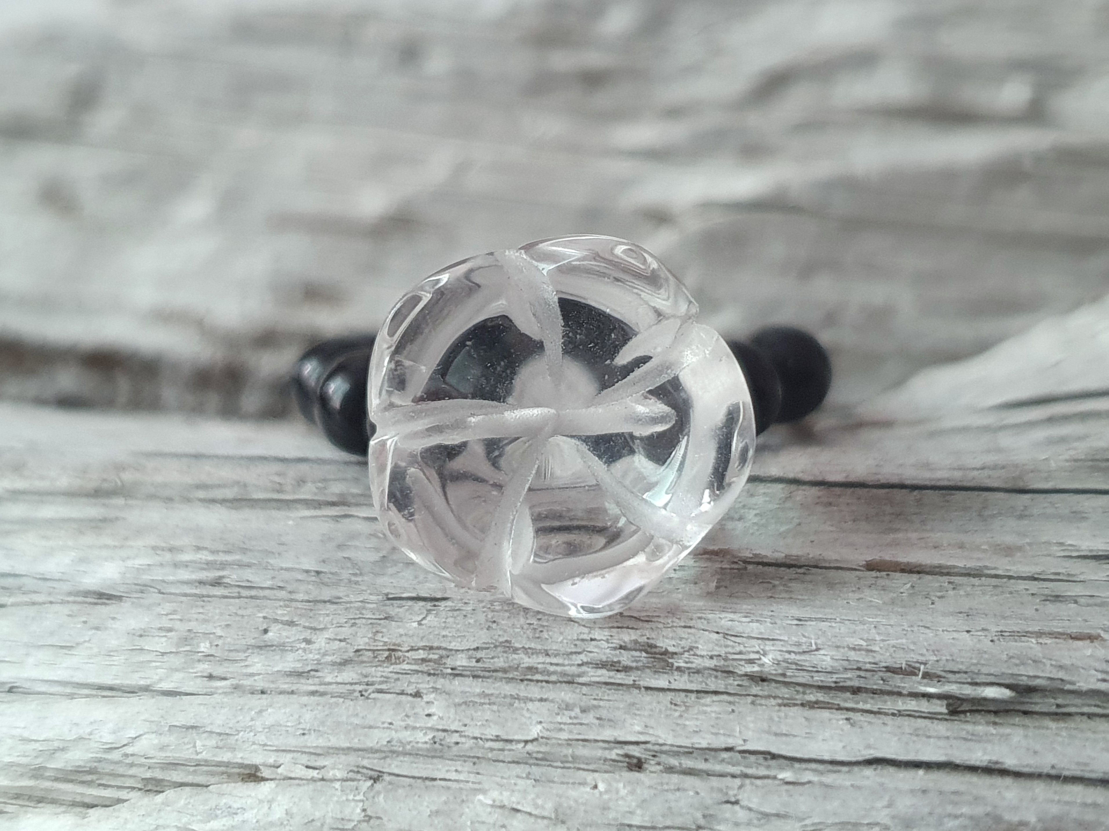 Ring skulpterad blomma i bergkristall med runda svarta onyxer ca. 4mm, ring på elastisk tråd.