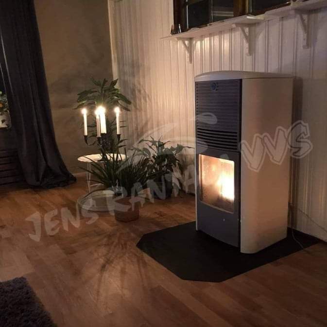 Pelletskamin Lilla Frö. I bakgrunden syns en ljusstake, krukväxt, hylla.