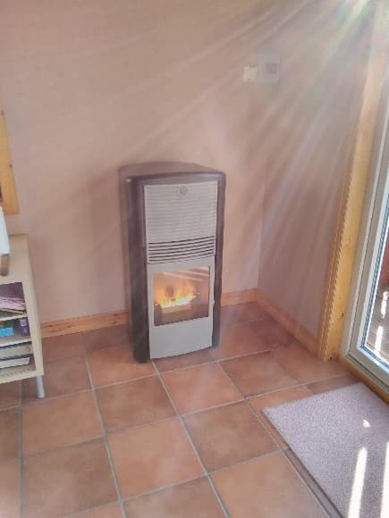 Skorstensfri pelletskamin Lilla Frö svart med grå front. Pelletskamin utan skorsten. Klinkergolv. Solen lyser in.