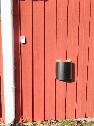 skorstensfri pelletskamin Lilla Frö svart med svart front, pelletskamin utan skorsten. På utsidan sitter denna. Röd fasad.