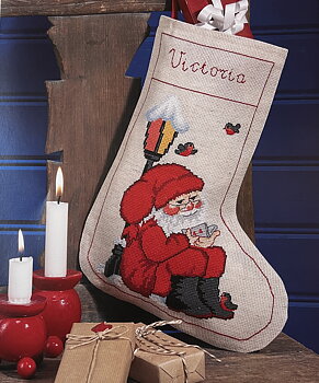 Julstrumpa. Tomten sitter vid lyktstolpe.