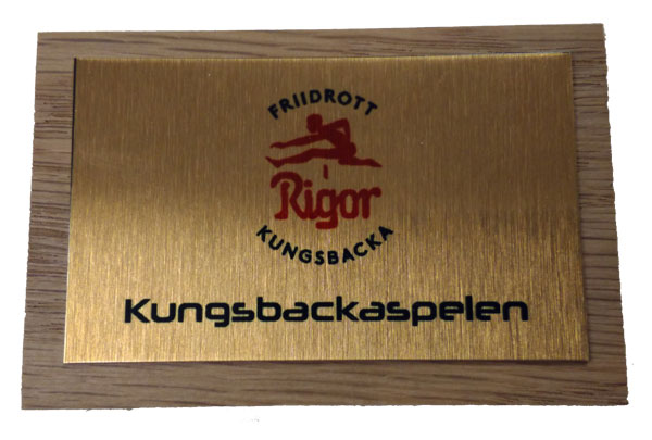 Plakett 75x50 mm i trä med monterad skylt i metall med eget motiv - I priset ingår valfritt motiv i färg och text.