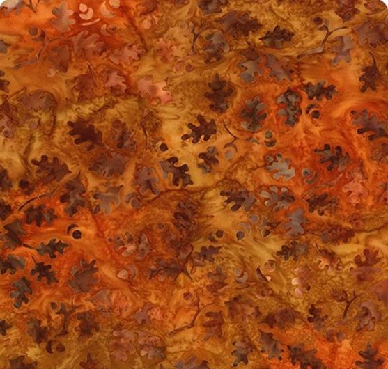 Orangefärgat batiktyg med löv mönster.