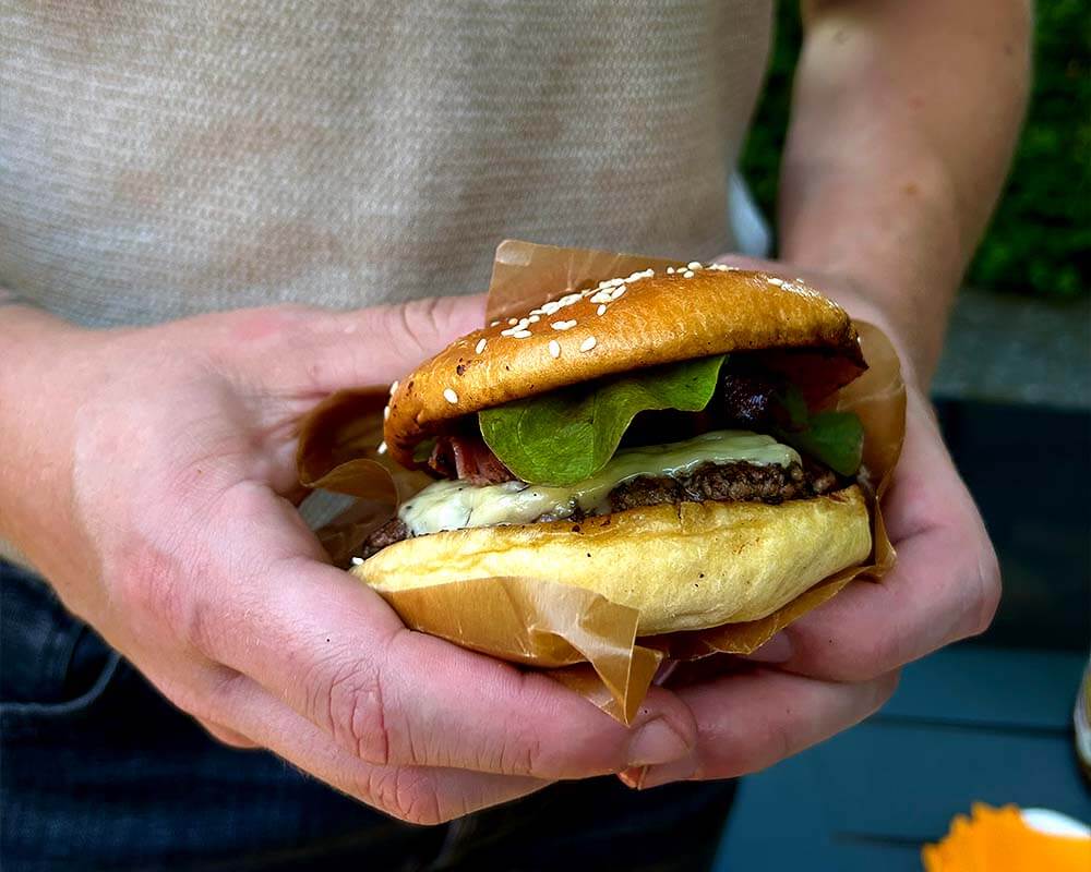 Hjemmelavet saftig burger tilberedt med hjælp af burgerpresser og stegebord i støbejern på grillen.